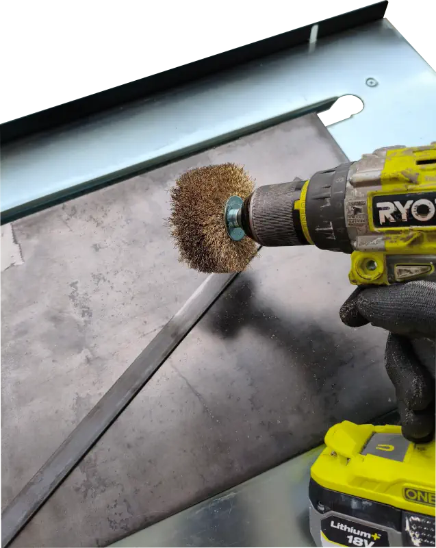 Embout brosse métallique cylindrique sur une visseuse sans fil pour décaper le fer plat.